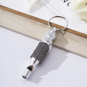 Close-up view of a silver aluminum alloy whistle keychain decorated with shiny rhinestones