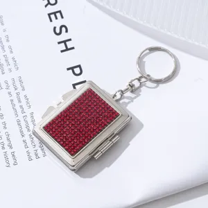 Detailansicht eines silbernen Mini-Schminkspiegel-Schlüsselanhängers mit roten Strass