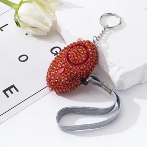 Close-up detail of a red rhinestone studded personal safety alarm with a keychain loop