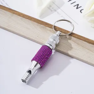 Detailed view of a silver aluminum survival whistle keychain featuring purple rhinestones