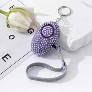 Detailed view of purple rhinestone personal self-defense alarm with lanyard