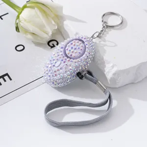 Detail of sparkling lavender rhinestone-studded personal safety alarm keychain with strap