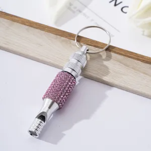 Detailed view of a silver aluminum survival whistle decorated with pink rhinestones