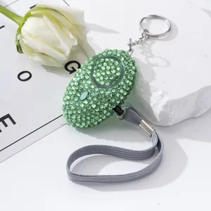 Close-up of a green rhinestone-encrusted personal safety alarm with keychain