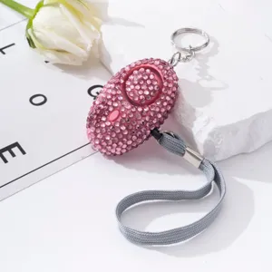 Close-up of a pink rhinestone personal safety alarm for women on a white stone