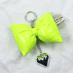 Detailed macro view of neon green leather bow keychain featuring a silver heart charm.