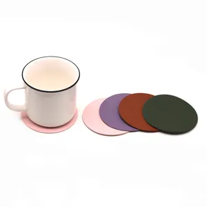 Vista detallada de posavasos de cuero redondos en varios colores con taza de cerámica blanca.