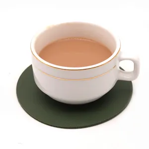 Primer plano de un posavasos minimalista de cuero verde oscuro con una taza blanca.