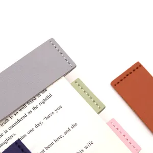 Close-up of minimalist faux leather bookmarks in assorted colors with neat stitching on book.
