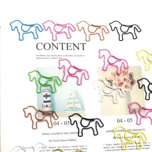 Creative horse-shaped colored wire paper clips scattered on an artistic magazine page.