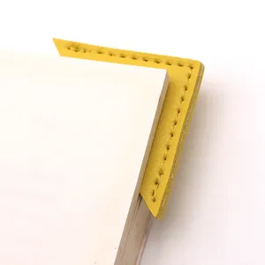 Close-up detail of yellow PU leather triangular bookmark clipped on paper page stationery.