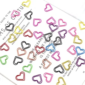 Primer plano de clips de papel de corazones coloridos dispersos en una página de libro.