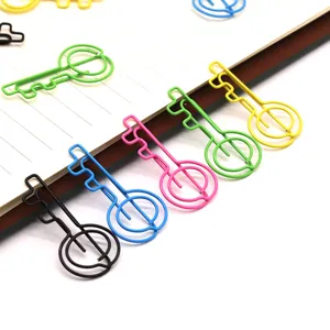 Gedetailleerde close-up van kleurrijke sleutelvormige metalen paperclips netjes georganiseerd op gelijnd papier.