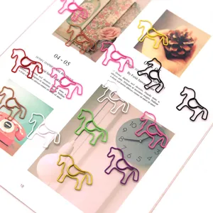 Macro view of colorful horse-shaped metal paper clips scattered on an open magazine page