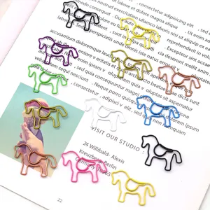 Detailed view of creative colorful horse-shaped metal paper clips on a book page.