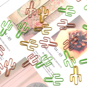 Gros plan de trombones métalliques mignons en forme de cactus sur fond de papier imprimé décoratif