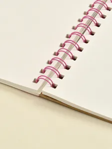 Nahaufnahme der Details eines weissen Skizzenbuches mit pinken Spiralringen und dickem Papier.