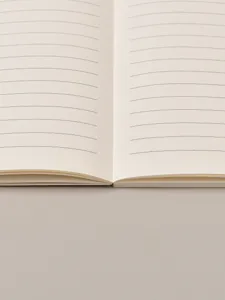 Close-up detail of the open ruled notebook showing smooth cream paper and clean lines.
