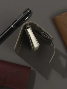 Gros plan sur le mini agenda à anneaux en cuir avec anneaux métalliques et porte-stylo.