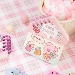 Cute house shaped spiral mini notebook with kawaii cartoon pig design and pink plaid background.