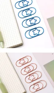 Close-up detail of cute star-shaped metal paperclips in blue and rose gold colors.