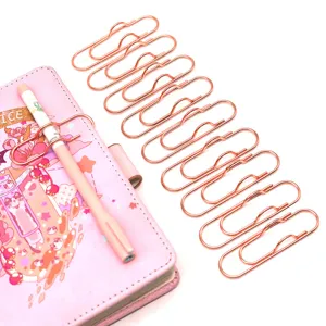 Dettaglio clip per penna e graffetta in metallo oro rosa, accessorio di cancelleria multifunzione.