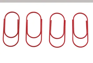 Detail view of red metal paper clips, neatly arranged on clean white surface for stationery use.