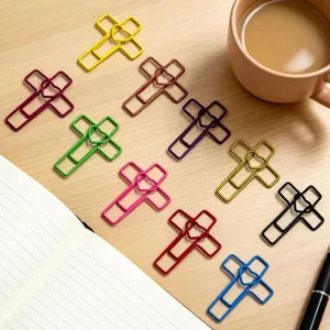Close-up detail view of colorful cross shaped metal paper clips and bookmarks arranged on wooden desk.