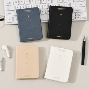 Mini cuaderno de bolsillo con páginas en blanco y diseño de estrellas doradas en la portada.