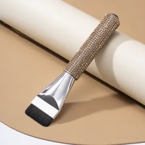Detail shot of a professional flat-head foundation brush featuring champagne rhinestone handle