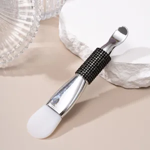 Detail view of dual-head silicone mask brush with rhinestone handle and metal scoop