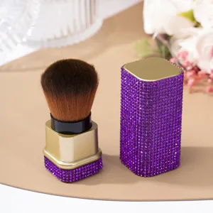 Close-up of a luxury purple rhinestone-covered nail dust and loose powder brush.