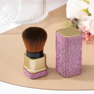 Detail of pink rhinestone-studded nail dust brush with gold-toned finish and cap.