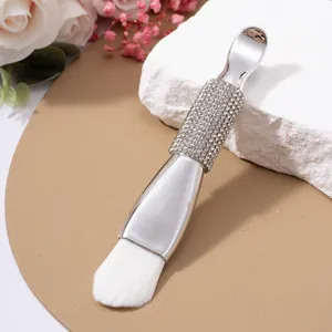 Detail view of a double-headed facial mask brush with a luxury rhinestone handle and spatula