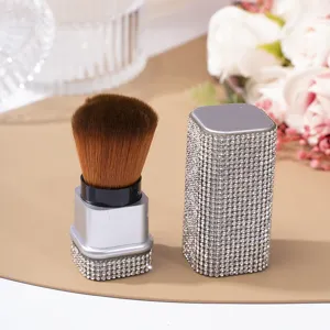 Detailed macro view of silver rhinestone nail dust brush and matching cap on beige mat