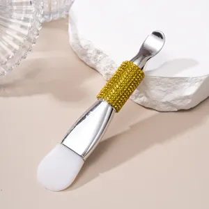 Detailed macro view of double-ended silicone facial mask brush with yellow rhinestone handle