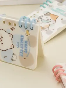 Detailed view of cute cartoon cat pattern spiral notebook with colorful plastic rings, compact size.