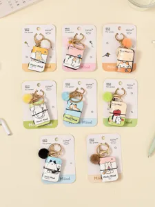 Mini notebook keychain detail, cute cat pendant with furry pom pom and metal clasp.
