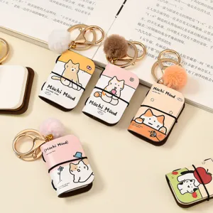 Mini PU leather notebook keychain with cute cat design and plush pom pom pendant for bags.