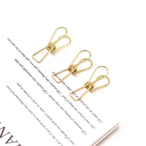 Gros plan sur de mini pinces à papier en métal doré, papeterie élégante pour le bureau.
