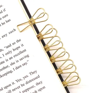 Petites epingles a papier dores en forme de poisson, marque-pages metalliques utiles.