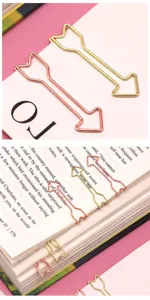 Close-up detail of creative arrow-shaped metal paper clips in gold and rose gold finish.