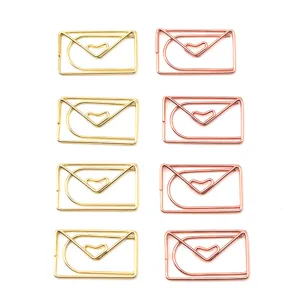 Detailansicht von briefumschlagförmigen Metall Büroklammern in Gold und Roségold mit Herz.