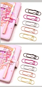 Detailansicht eines kreativen herzförmigen Metall-Stiftclips an einem rosa Notizbuch