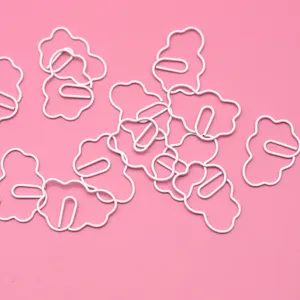 Primer plano de clips de papel blancos en forma de nube sobre fondo rosa detalle foto