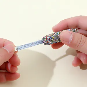 Detail eines tragbaren Mini-Rollmaßband-Schlüsselanhängers mit bunten Strasssteinen