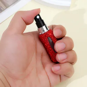 Macro view of a 5ml red rhinestone handmade perfume atomizer bottle held in a hand for scale.