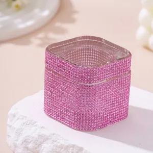 Detail eines rosa strassbesetzten quadratischen Kristallglases mit Deckel auf Stein