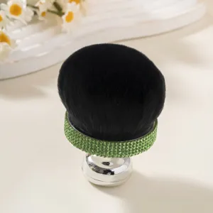 Close-up of mushroom head powder brush with green rhinestone ferrule and black bristles.