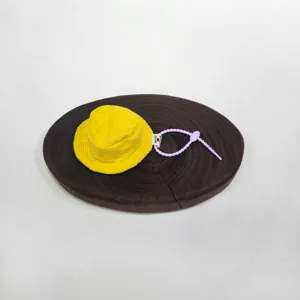Détail d'un mini étui à écouteurs en forme de bob jaune en velours côtelé sur bois